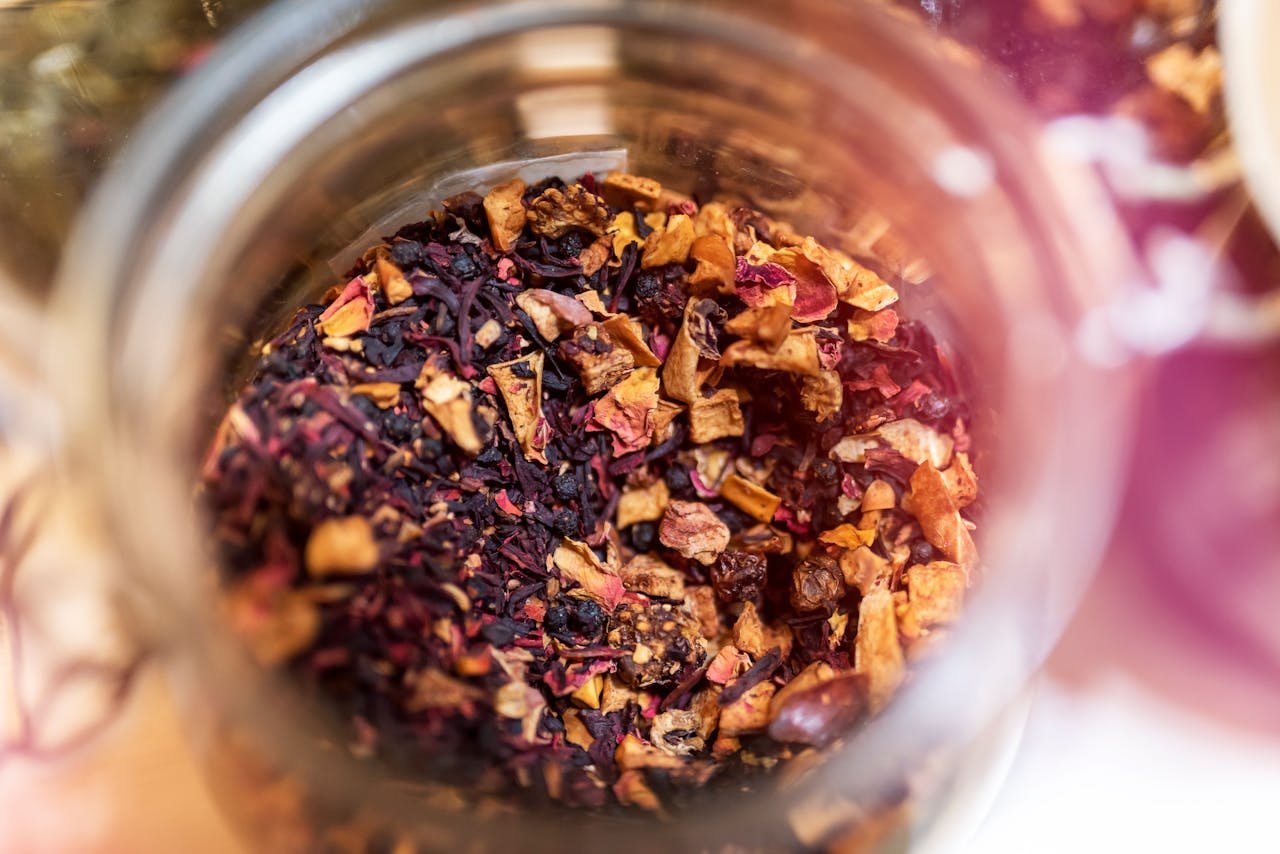 From above of glass jar with dry aromatic fruit tea against blurred background in daylight