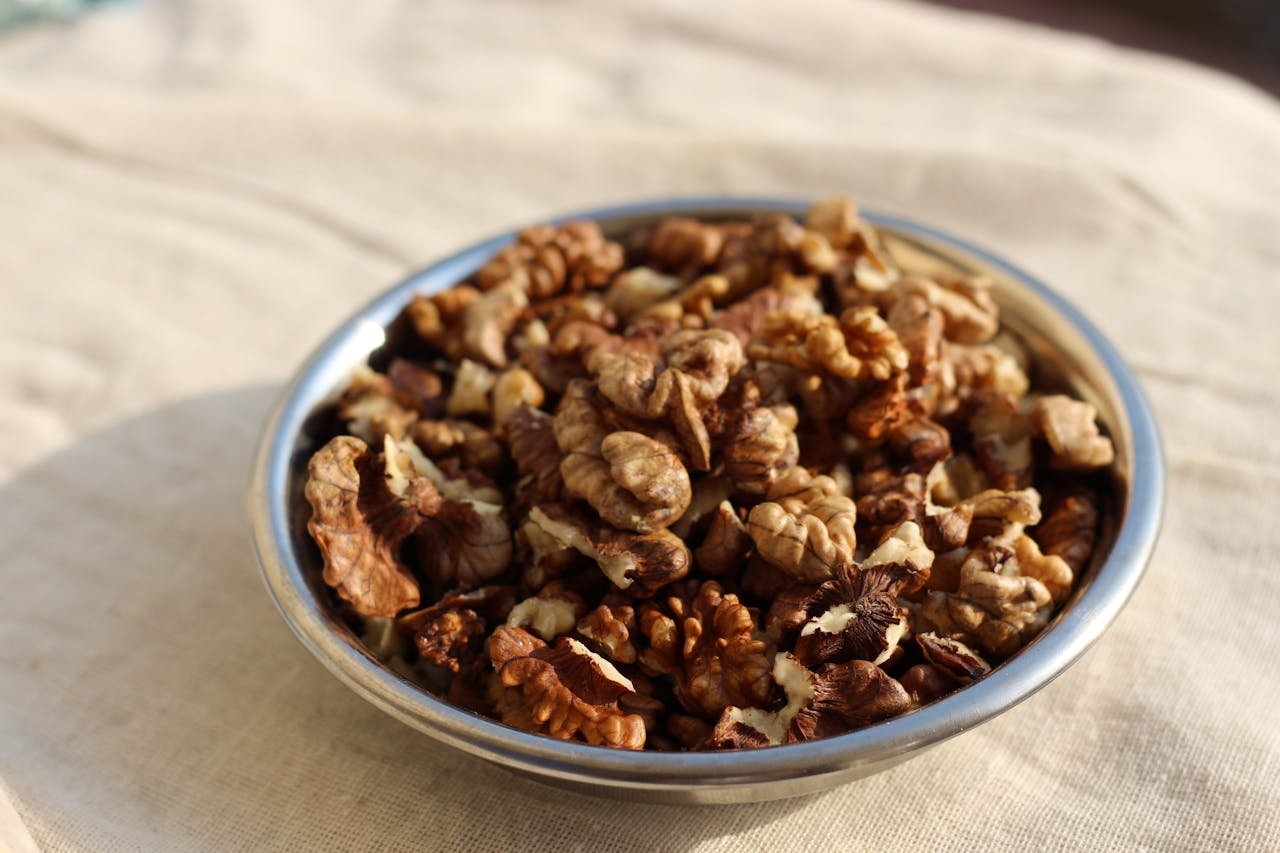 Close-up of walnuts in a metal bowl outdoors, highlighting their natural texture and health benefits.